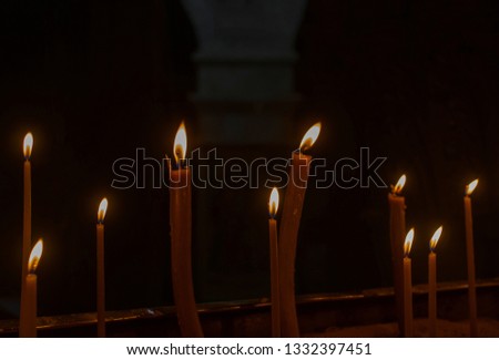 Burning wax candles in the church on a dark background 