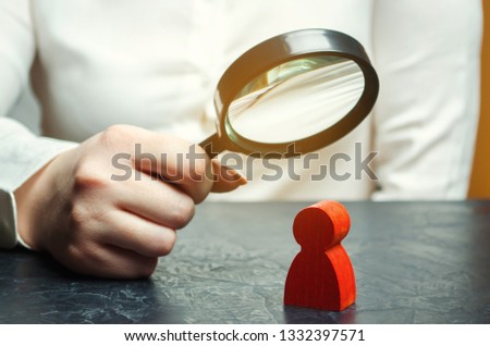 Business woman examines a red man's figure through a magnifying glass. Analysis of the personal qualities of the employee. Characteristic. Unreliable employee. Toxicity in the staff of workers Royalty-Free Stock Photo #1332397571