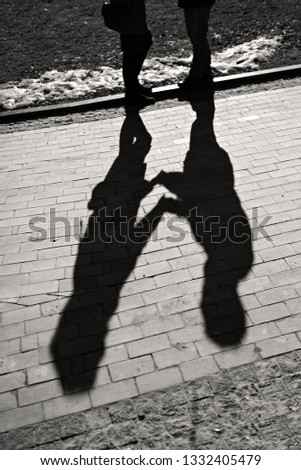 Shadows of couple in love on a walk in the city on sunny day. Man and women holding hands and looking on each other, city outdoor, black and white photo