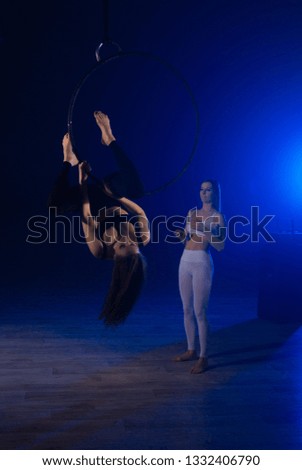 Duet gymnasts girls aerial acrobatics on the ring on the background of blue smoke