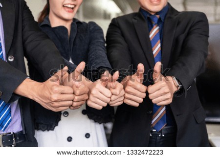 Many happy business people make thumbs up sign join hands together with joy and success. Company employee celebrate after successful work project. Corporate partnership and achievement concept.