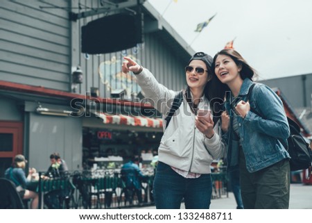 group of asian chinese lady backpacker looking cellphone online map finger pointing searching direction while going to next sightseeing spot. young girls visit Old Fishermans Wharf shopping outdoor.
