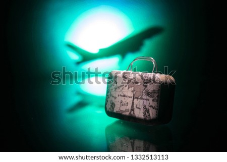 Summer vacation concept. Traveler suitcase with airplane in background. Artwork table decoration with empty space for your text. Focus on suitcase.