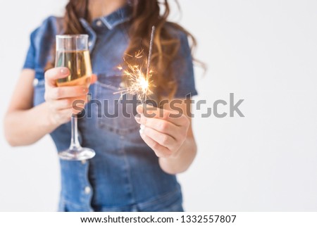 Celebration, drinks and holiday concept - close up of young woman with sparkler and glass of champagne on white background