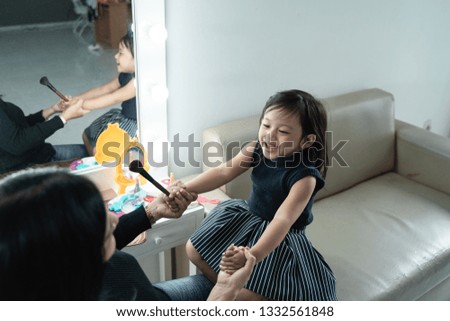 happy mother and kid playing with make up looking at mirror