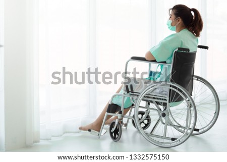 Asian woman sitting on a wheelchair looking outside the window in a hospital, patient with depression and anxiety(major depressive disorder). mental health problems concept.