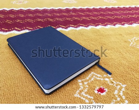 a closed blue note book on a decorated carpet