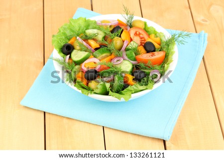 Fresh salad in plate on wooden table