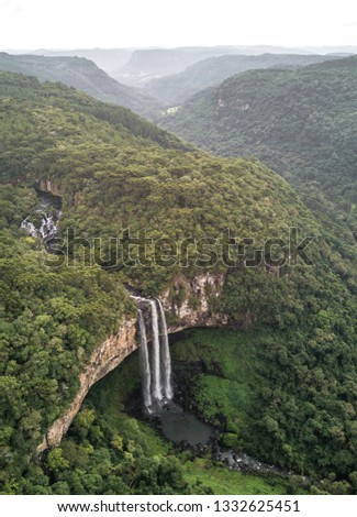 Aerial view of tall cliff side waterfalls surrounded by a lush green forest in Canela, Brazil. South America.