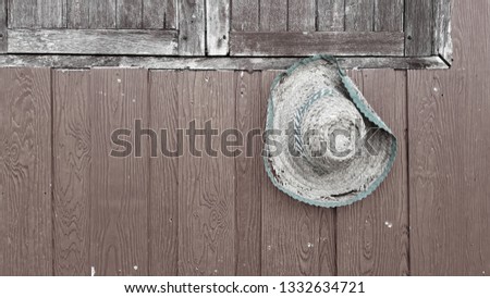 Broken and old straw hat Hung on the side of the house wall