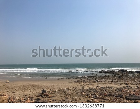 Pictures of the sandy beach, the scattered pebbles,  white wave constantly shore and the sea on a clear day under the blue sky, Phetchaburi, the lower central of Thailand.
