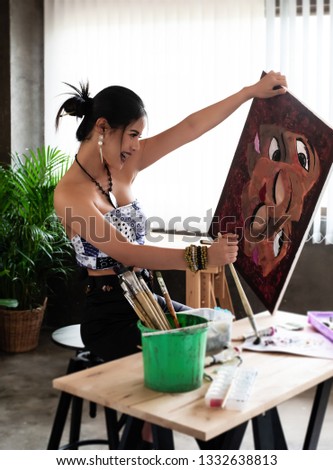 Tha young artist doing art painting at her artwork studio,with happy feeling,blurry light around