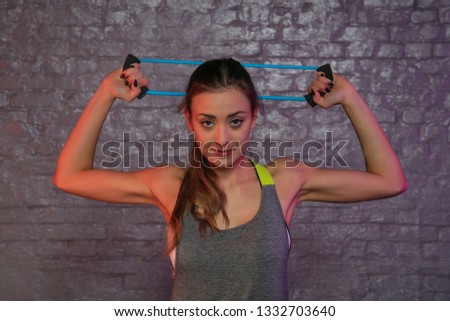 young beautiful girl practicing at the gym with rubbers