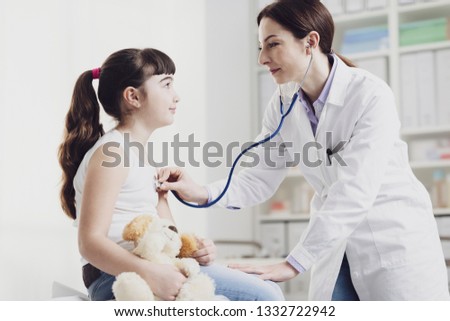 Female doctor examining a cute smiling girl with a stethoscope, the mother is next to her, children and healthcare concept