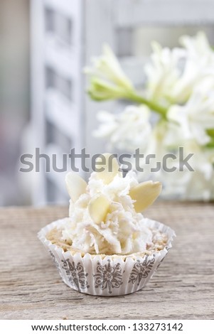 Pretty small cupcakes, lavishly decorated, on wooden table.