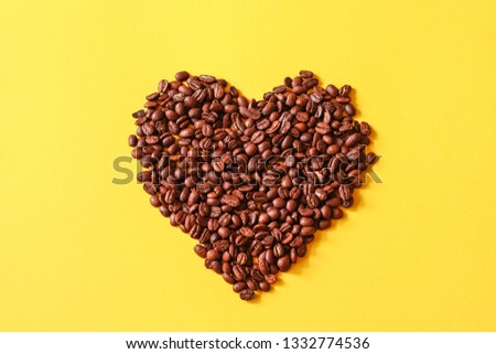 Coffee beans in the shape of  the heart  on yellow background