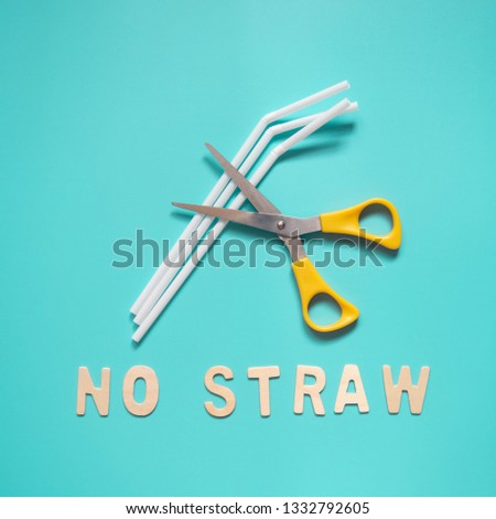 Stop using plastic straws concept - Yellow metal scissors cut white disposable plastic straws with "NO STRAW" words on aquamarine color background. Plastic pollution and environmental issue.
