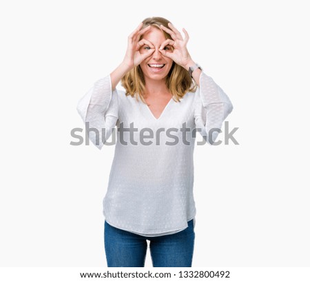 Beautiful young elegant woman over isolated background doing ok gesture like binoculars sticking tongue out, eyes looking through fingers. Crazy expression.