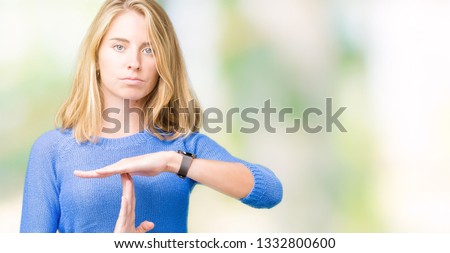 Beautiful young woman wearing blue sweater over isolated background Doing time out gesture with hands, frustrated and serious face