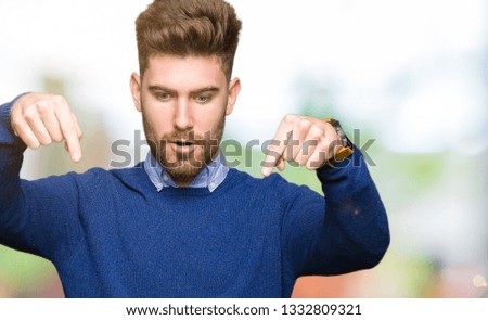 Young handsome bussines man Pointing down with fingers showing advertisement, surprised face and open mouth