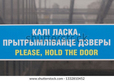 Please, hold the door blue sign in english and belarusian language
