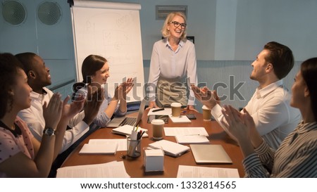 Happy diverse team people young employees interns applaud thank old happy mentor coach for good presentation training celebrating success support leader congratulating, appreciation gratitude, late Royalty-Free Stock Photo #1332814565