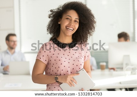 Happy confident african american business woman employee holding digital tablet looking at camera standing in office, smiling millennial mixed race female intern manager young professional portrait Royalty-Free Stock Photo #1332814703