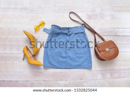 Blue jeans skirt with yellow high hell shoes and sunglasses,handbag  on white wooden background
