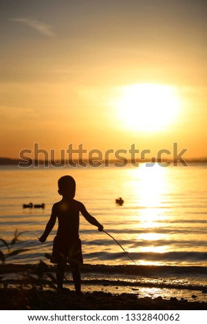 sunset with baby boy on the beach. boy fisherman