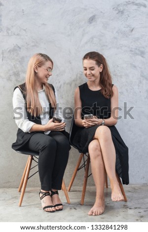  young Business people are Using smartphones and display technology, Two young women sit and read news online and search for information on mobile phones And talked well