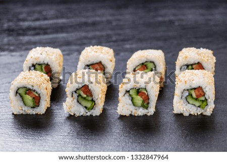 Vegeterian makizushi roll with cucumber and tomato arranged on slate plate background