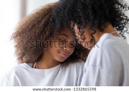 Mixed race loving mommy and teen daughter close to each other touching foreheads with closed eyes enjoy time together, tender moment strong connection, bonding, family relative people and love concept Royalty-Free Stock Photo #1332865598