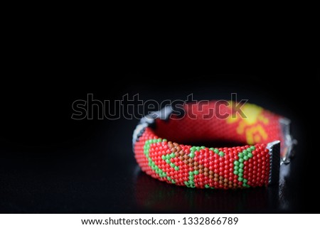 Red bracelet with funny panda on a dark background close up