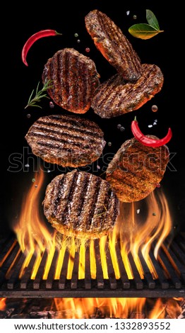 Cooking Hamburger cutlet. Conceptual picture. Steak with spices and cutlery under burning grill grate.