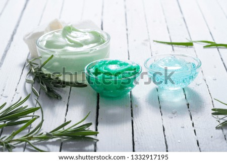 cosmetic cream product samples and lavender leaves on white wooden table background
