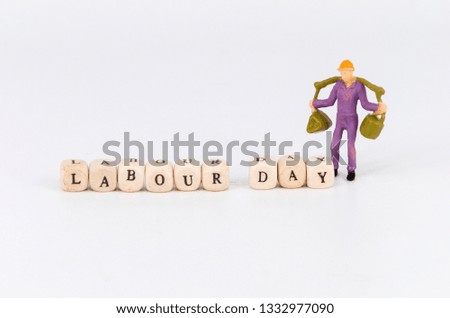 Labour day concept. Word labour day on wooden cubes with miniature worker on white background. Selective focus.