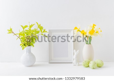 Home interior with easter decor. Mockup with a white frame and yellow daffodils in a vase on a light background