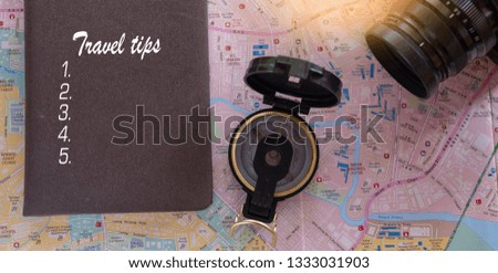 Travel tips text message on note book with map, vintage clock, camera and compass on wooden table.