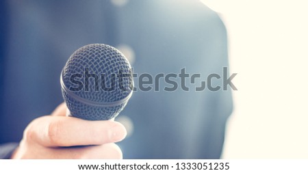 Interview: Black microphone in the foreground, man with blue shirt in the blurry background