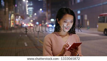 Woman look at cellphone in city at night