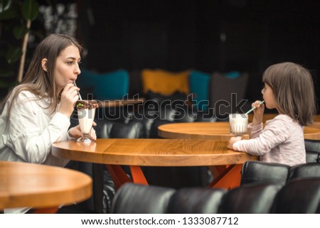 Happy young women mother with children sitting at dinner table and talking in restaurant or cafe. In Leisure and communication with children restaurant