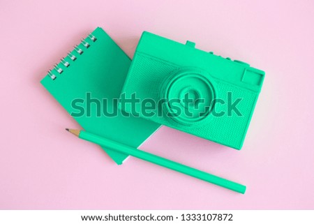 Flat lay of retro camera and notebook with pencil on pastel pink background minimal creative concept.