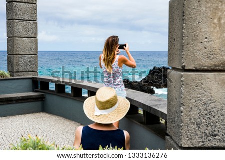 Ocean landscape.  A young woman takes pictures on the phone ocean. Sitting next to another woman. Women are depicted behind. Selective focus. Copy space