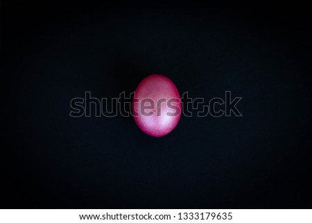 purple painted egg isolated on black background; shiny, marbled, oval-shaped creative object