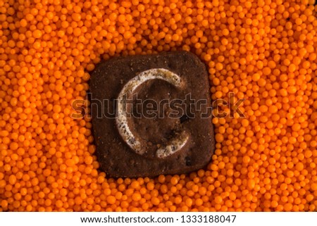 Chocolate cookies with letters on the background of orange sweet balls