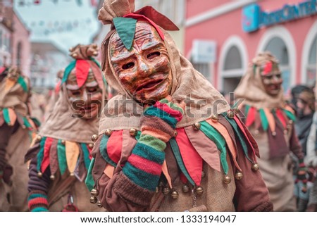 Friendly carnaval figure in brown, green, red robe shows hand gesture. Carnival in southern Germany - Black Forest