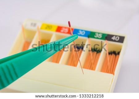 gutta-percha pins in a set of different sizes for root canal fillings, one pin close-up in tweezers, material for endodontic fillings Royalty-Free Stock Photo #1333212218