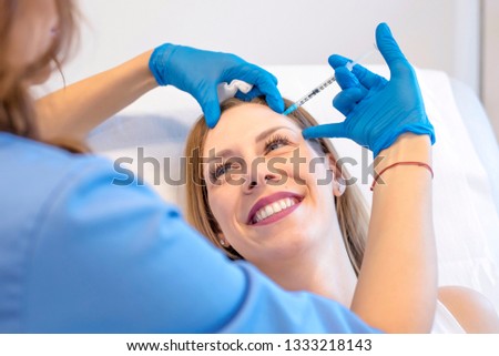 Female doctor doing hyaluronic acid injections on the face of young woman in a beauty clinic