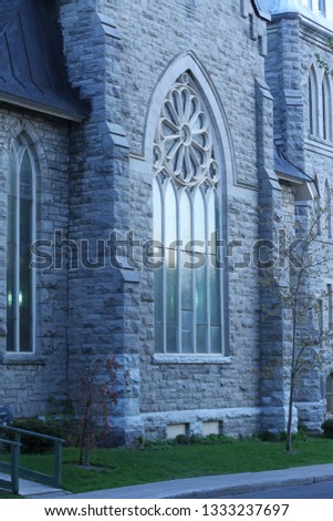 Arched glass window of an old stone church photographed at twilight for a blue tint.