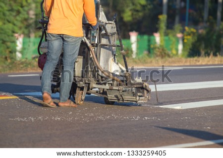 Thermoplastic spray marking machine during road construction. Worker painting white line on the street surface (Road worker painting)